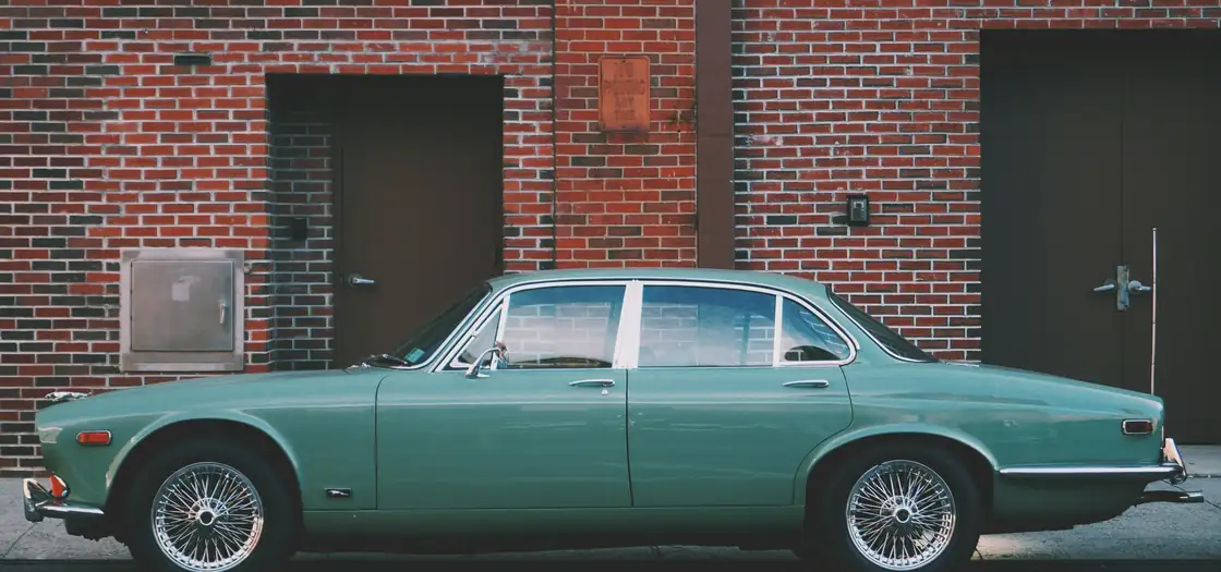 Vista lateral de un elegante Jaguar verde clásico aparcado